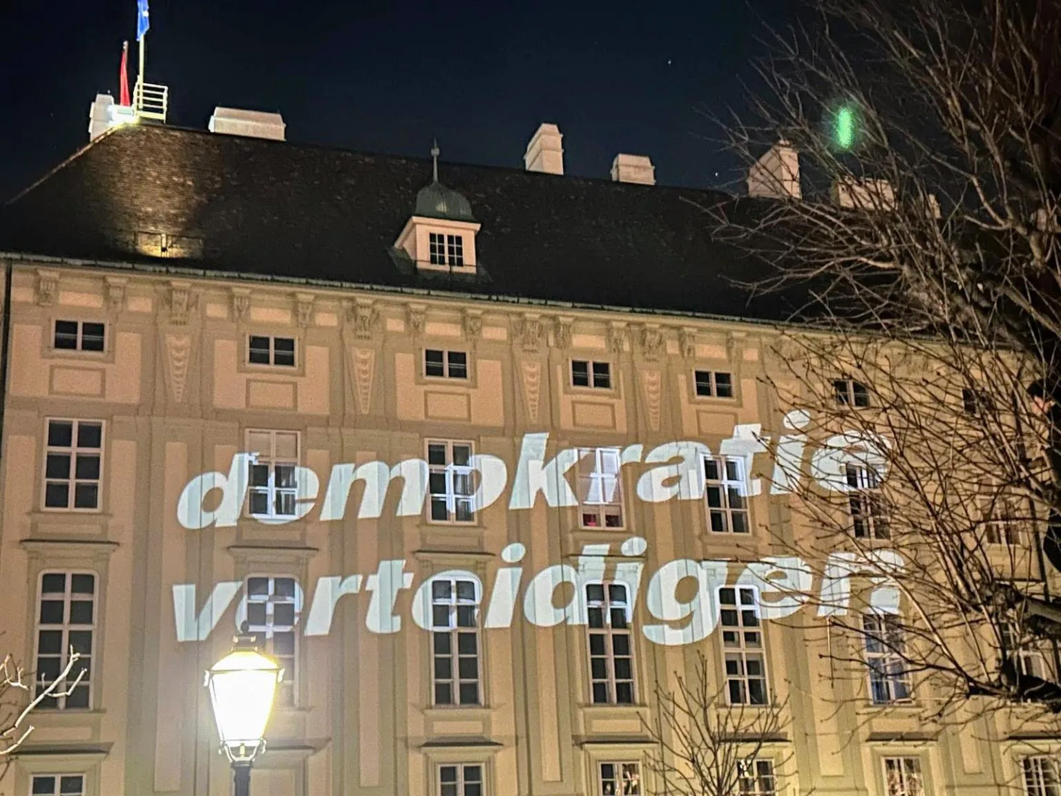 Projektion „demokratie verteidigen“ auf einer Fassade der Wiener Hofburg bei Nacht